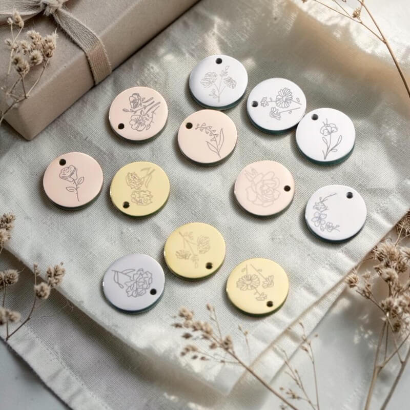 Set of round decorative tags with floral designs on a textured surface with dried flowers.